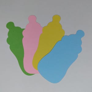 Puede incluir: Cuatro recortes de papel en forma de biberón en verde, rosa, amarillo y azul.
