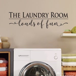 May include: White washing machine with a silver door and a black control knob. The wall behind the machine has a black vinyl decal that reads "The Laundry Room loads of fun".