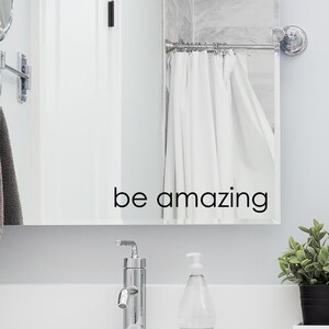 May include: A bathroom mirror with a white shower curtain and the text "be amazing" written on the mirror.