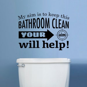 Könnte beinhalten: Ein schwarz-weißes Badezimmer-Schild mit der Aufschrift "Mein Ziel ist es, dieses Badezimmer sauber zu halten. Dein Ziel wird helfen!" mit einem Zielsymbol neben dem Wort "Ziel".