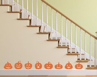 May include: A set of nine orange pumpkin face decals for Halloween decorating. The decals are placed on a white staircase with a wooden handrail.