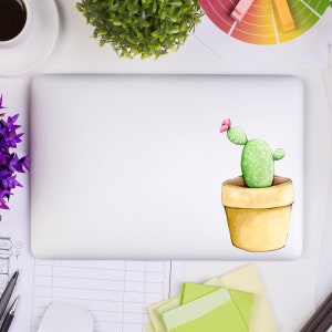 May include: A white laptop computer with a green cactus in a yellow pot with a pink flower on top. The cactus is on a sticker on the laptop.