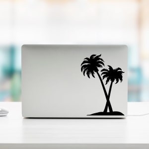 May include: A silver laptop computer with a black silhouette of two palm trees on the lid.