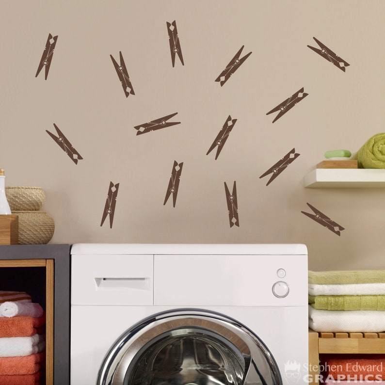 May include: A white washing machine with a brown wall behind it. The wall has a pattern of brown clothespins.