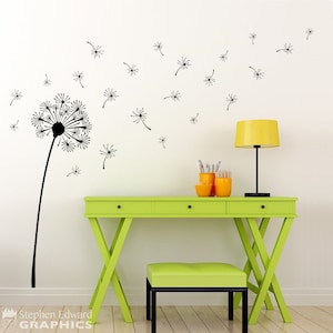 Peut inclure: Un autocollant mural noir représentant un pissenlit avec des graines s'envolant, à côté d'un bureau et d'un tabouret vert citron. Une lampe jaune et des accessoires de bureau orange sont sur le bureau. Le mur est blanc.