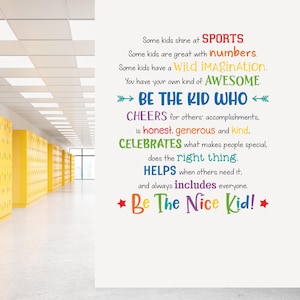 May include: A white wall with colourful text that reads "Be The Kid Who" and "Be The Nice Kid!" in a school hallway. The text is in various colours and fonts. Yellow lockers line the hallway.