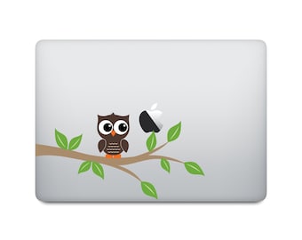 May include: A brown owl with large eyes sits on a branch with green leaves. The owl is perched on a branch with a partially visible white apple logo behind it. The image is a laptop skin design.