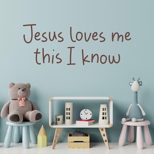 Puede incluir: Una pared azul claro con las palabras "Jesus loves me this I know" escritas en marrón. Hay un oso de peluche marrón sentado en un taburete azul claro, una estantería blanca con un reloj y artículos decorativos, y una jirafa azul sentada en un taburete rosa.