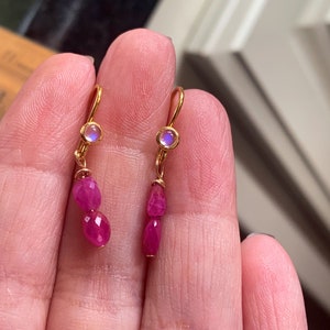 May include: Gold earrings with a pink gemstone and a small iridescent stone.