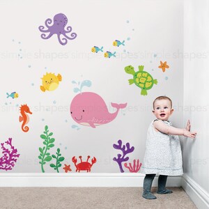 May include: Wall decals featuring a whimsical underwater scene with a pink whale, purple octopus, and various colorful sea creatures. The decals include fish, a seahorse, a turtle, and coral, creating a playful ocean theme. The text "simple shapes" is visible.