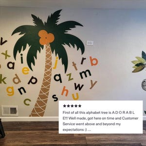 May include: A wall mural featuring a large green palm tree with an orange coconut and a brown trunk. Colorful alphabet letters are scattered around the tree. The text in the image says, "First of all this alphabet tree is ADORABLE!!!"