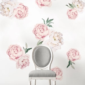 Può includere: Una sedia bianca con seduta e schienale imbottiti grigi, decorata con adesivi murali floreali rosa e bianchi. Gli adesivi raffigurano peonie in stile acquerello con foglie verdi.