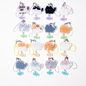 May include: A collection of cat-shaped keychains in various colors and patterns. Each keychain has a different personality type abbreviation, such as ENTJ or INFP, on a small fish-shaped tag. The keychains are attached to a metal clasp with a colorful lanyard.
