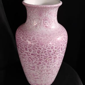 May include: A vase with a flared rim and a rounded body, featuring a textured, crackled finish in shades of light pink and white. The interior of the vase is smooth and white, contrasting with the intricate, web-like pattern on the exterior surface.