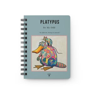 May include: Spiral-bound notebook with a teal cover featuring the word "PLATYPUS" and the phrase "Be My Odd." The cover art includes a colorful platypus with a mouse on its back. The notebook has a black spiral binding.
