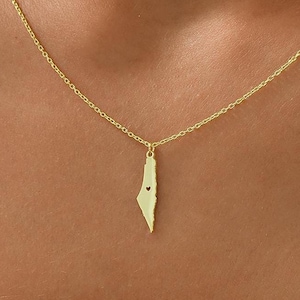 May include: A gold necklace with a pendant shaped like the outline of Israel, with a small heart cut out in the center.