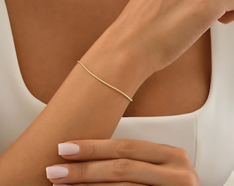 Könnte beinhalten: Ein schlichtes goldenes Kettenarmband am Handgelenk einer Person.
