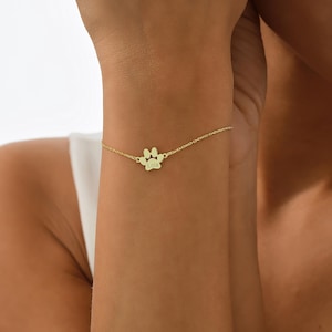 May include: Gold paw print charm bracelet with the name "Lola" engraved on the charm.