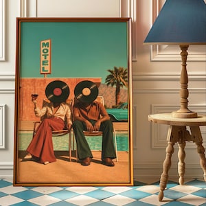 May include: A framed wall art print depicting two figures sitting in chairs by a pool, each with a black vinyl record for a head. The scene includes a motel sign, a palm tree, and a turquoise car. The figures wear retro-style clothing.