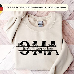 Puede incluir: Sudadera color crema con la palabra "Oma" en negro, adornada con detalles florales. Debajo, los nombres "Michael Sarah Lukas". El texto "SCHNELLER VERSAND INNERHALB DEUTSCHLANDS" se encuentra en la parte superior.