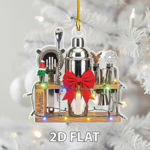 May include: A clear acrylic Christmas ornament shaped like a bar setup, featuring a cocktail shaker, bar tools, and a red bow. The ornament is decorated with a string of colorful lights and the text "NAME" and "2D FLAT".