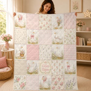 Può includere: Una coperta trapuntata con un design patchwork a quadretti rosa, motivi floreali e illustrazioni di anatre bianche. Diverse anatre indossano cuffiette o fiocchi rosa e un quadrato mostra il nome Claire Elaine in caratteri corsivi rosa.