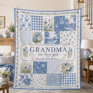 Könnte beinhalten: Eine blau-weiße Patchwork-Decke mit Blumenmustern, Vichy-Karos und einem zentralen rechteckigen Feld mit dem Text "GRANDMA we love you", gefolgt von den Namen "Ethan", "Olivia" und "Mason", die durch Herzsymbole getrennt sind.