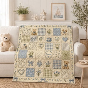 May include: A quilted throw blanket featuring a patchwork design in shades of cream, light blue, and sage green. The pattern includes illustrations of teddy bears, bows, hearts, flowers, a teacup, and a slice of cake, with the name Lucas printed.