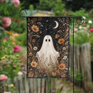 May include: A rectangular garden flag featuring a central white ghost figure surrounded by a dark background filled with orange and brown autumn flowers, ferns, and foliage. A white crescent moon and small stars are visible at the top center.