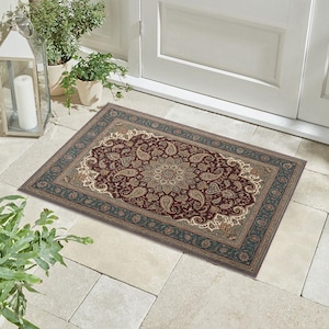 May include: A rectangular outdoor rug with an ornate paisley design. The rug features a burgundy center with cream and teal accents. The border is teal with a repeating pattern. The rug is placed on a stone patio near a white door.