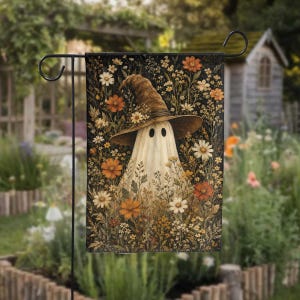 May include: A rectangular garden flag featuring a white ghost wearing a brown witch hat adorned with small flowers. The ghost is surrounded by a dense field of orange, white, and yellow wildflowers set against a dark, textured background.