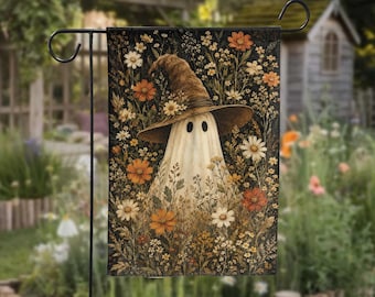 May include: A rectangular garden flag featuring a white ghost wearing a brown witch hat adorned with small flowers. The ghost is surrounded by a dense field of orange, white, and yellow wildflowers set against a dark, textured background.