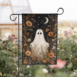 May include: A rectangular garden flag featuring a white ghost centered against a dark background. The ghost is surrounded by a border of orange and brown autumn flowers, ferns, and foliage. A crescent moon and small stars appear at the top.