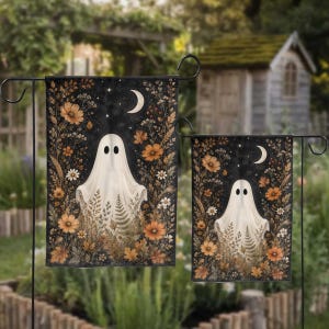 May include: Two rectangular garden flags featuring a white ghost centered against a dark starry night sky with a crescent moon. The design is framed by orange and brown autumn flowers, dried grasses, and foliage, creating a seasonal botanical display.