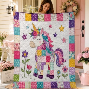 Könnte beinhalten: Eine rechteckige Patchwork-Decke mit einem zentralen weißen Feld und einer großen Einhorn-Illustration. Das Einhorn hat einen Blumenkranz, eine mehrfarbige Mähne und einen Schweif. Die Decke ist mit bunten Blumenquadraten und Sternen umrandet.