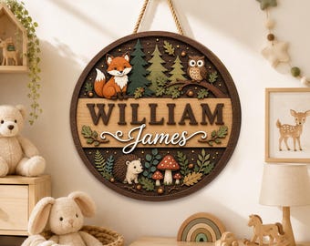 May include: A circular wooden wall sign featuring a 3D relief design of a fox, an owl, a hedgehog, and mushrooms in a forest setting. The sign displays the name William James in dark brown and white lettering, suspended by a thick rope.