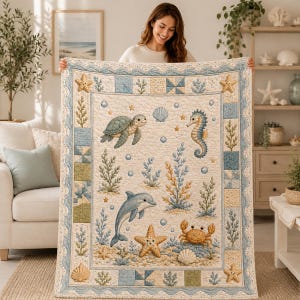 May include: A rectangular quilt featuring a cream-coloured centre panel with illustrations of a sea turtle, seahorse, dolphin, crab, starfish, and seashells amidst seaweed and bubbles. The border has a blue wave pattern and patchwork squares.
