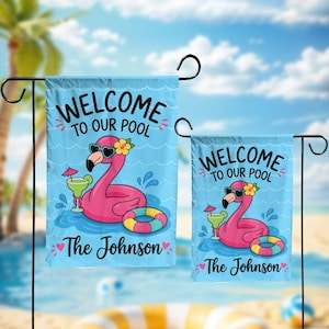 May include: Two light blue garden flags featuring a pink flamingo wearing heart-shaped sunglasses and a yellow flower. The text reads Welcome to our pool and The Johnson. A green cocktail with a pink umbrella and a colorful pool float are included.