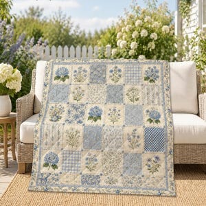 May include: A rectangular quilt featuring a patchwork design of alternating squares in shades of blue, cream, and white. The pattern includes various floral motifs, including hydrangeas and wildflowers, alongside small-scale gingham and striped prints.