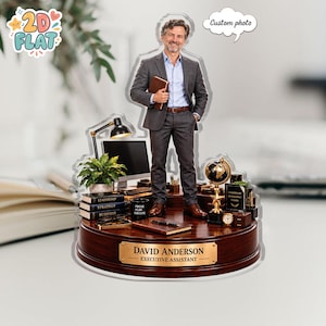 Könnte beinhalten: Ein personalisiertes Schreibtisch-Ornament aus Acryl mit einer stehenden Figur im grauen Anzug, die ein Notizbuch hält. Der Sockel aus dunklem Holz trägt ein goldenes Schild mit der Aufschrift DAVID ANDERSON EXECUTIVE ASSISTANT. Inklusive Globus.