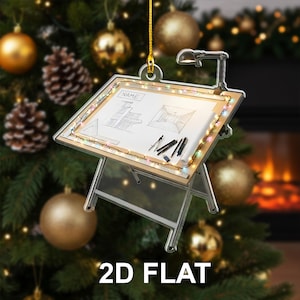 May include: A clear, 2D flat ornament shaped like an architect's drafting table, with a drawing, pens, and a lamp. The word "NAME" is visible on the top left. The ornament is decorated with small, colorful lights and the text "2D FLAT" is at the bottom.