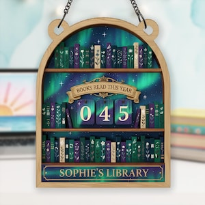 May include: Wooden bookshelf-shaped sign with a decorative design. The sign features a starry night sky background with a green and blue aurora borealis effect. The sign reads "BOOKS READ THIS YEAR" and "045". The bottom of the sign reads "SOPHIE'S LIBRARY".