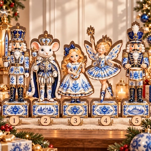 Puede incluir: Un conjunto de cinco figuras decorativas que incluye un cascanueces con espada, un rey ratón coronado, una niña con violín, un hada con alas y un cascanueces tamborilero, todos decorados con patrones florales azules y blancos sobre bases.