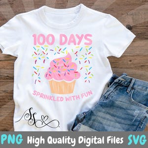 以下が含まれることがあります： 「100 Days Sprinkled With Fun」という文字と、カラフルなスプリンクルがかけられたピンクのカップケーキが描かれた白いTシャツ。