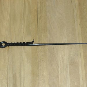 May include: A black metal fireplace poker with a twisted handle and a hook on the end.