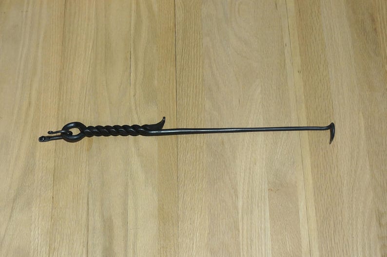 May include: A black metal fireplace poker with a twisted handle and a hook on the end.