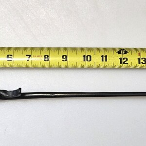 May include: A black metal fireplace poker with a twisted handle and a hook on the end. The poker is 16 inches long.