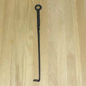 May include: A black metal fireplace poker with a twisted handle and a hook at the end.