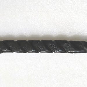 May include: A black metal fireplace poker with a twisted handle and a ring at the end.