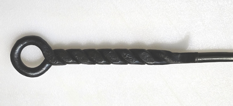 May include: A black metal fireplace poker with a twisted handle and a ring at the end.